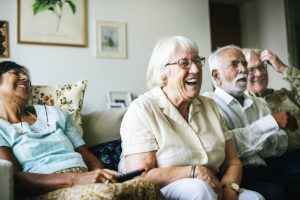 seniors laughing at tv during Senior Living Programs in garland tx